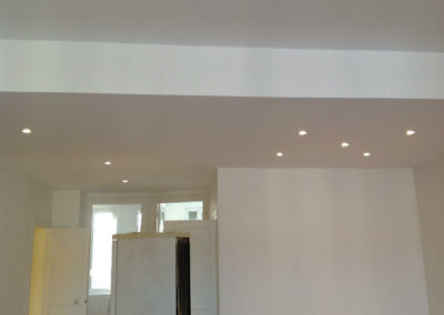 Pièce de vie entièrement refaite avec faux-plafond et série de spots led encastrés, offrant un éclairage homogène