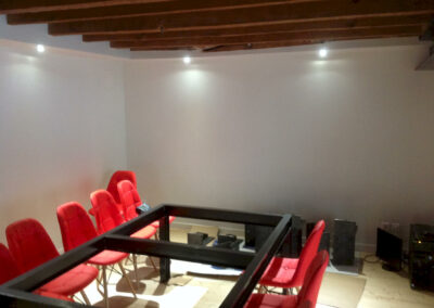 Salle de réunion du cabinet d’avocats, chaises rouges et éclairage mural sous poutres apparentes