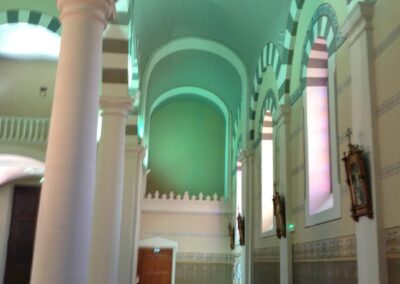 Vue latérale de la nef de l’église de saint-étienne-les-houlières, colonnes et baies éclairées en led mettant en valeur l’architecture intérieure