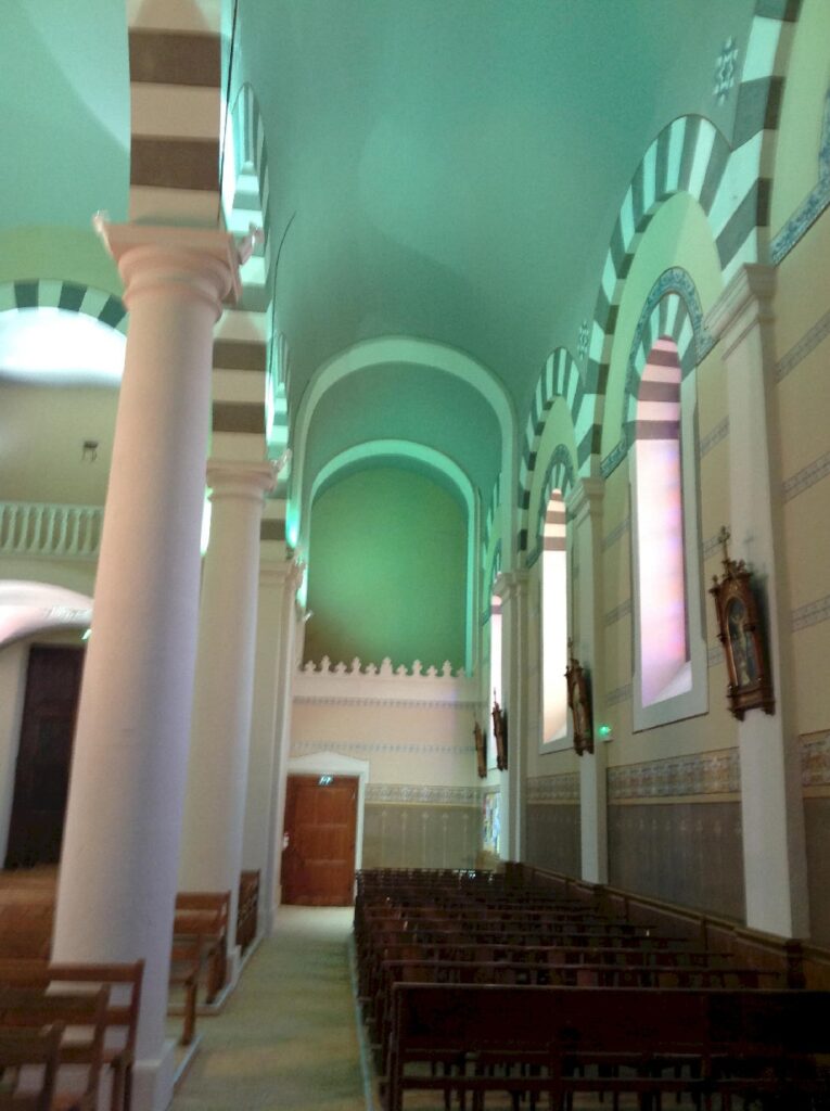 Vue latérale de la nef de l’église de saint-étienne-les-houlières, colonnes et baies éclairées en led mettant en valeur l’architecture intérieure